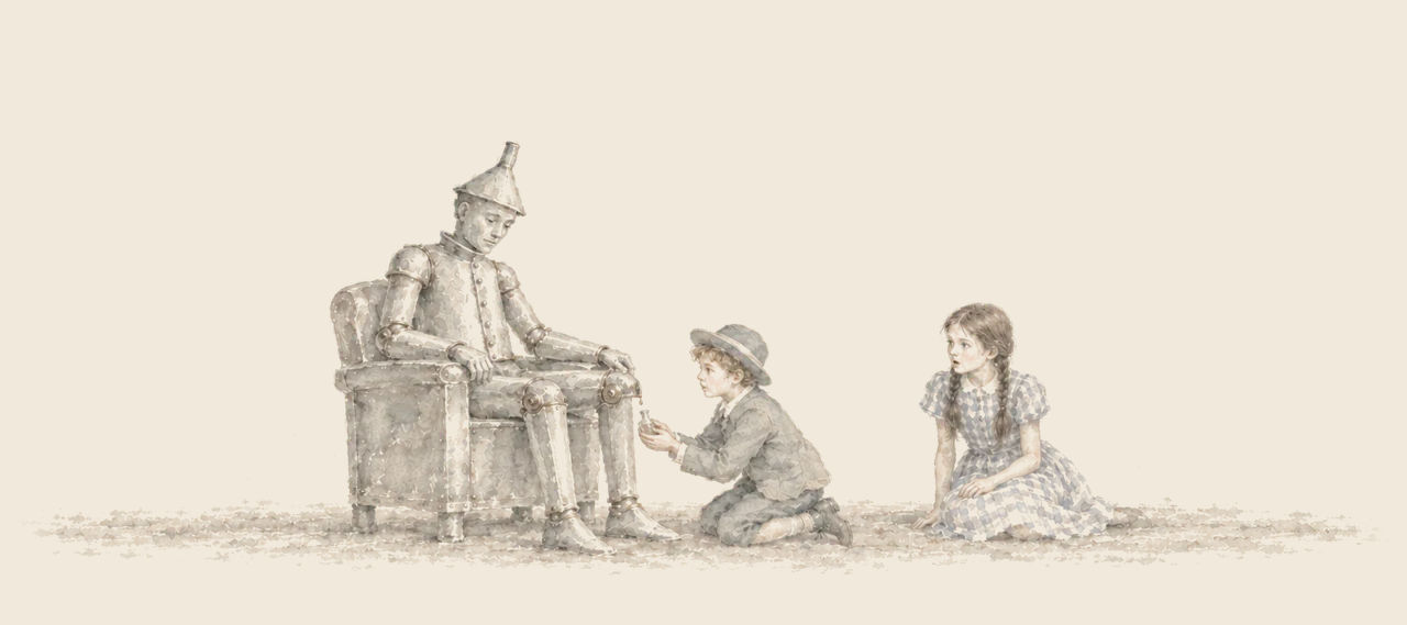 The Tin Woodman sits in a tin armchair while Ojo kneels to put a drop of oil from a tiny vial on his knee, and Dorothy sits watching.